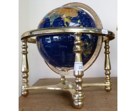 A table globe made from polished hard stone and mounted in a brass frame.