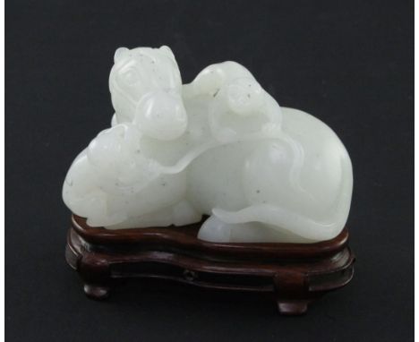 A Chinese white jade carving of two monkeys clambering on a recumbent horse, 20th century, 9cm, wood stand A Chinese white ja