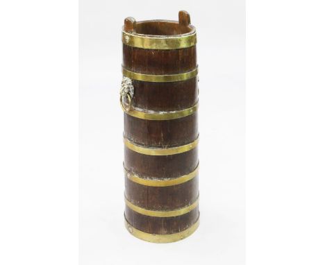 A tall oak barrelled stick stand, 28.5in. A tall oak barrelled stick stand, brass bound with lion mask ring handles, 28.5in.