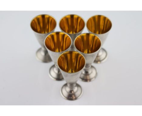 A set of six silver Russian tot glasses (875 fineness), gilt interior to tapered bowls, inverse baluster form step and flared