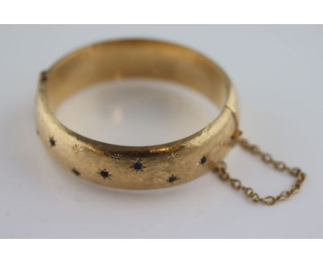 A Victorian style sapphire and 9ct yellow gold hinged bangle, seven gypsy star set round mixed cut sapphires amongst twelve e