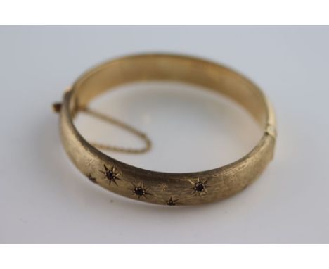 A ruby 9ct yellow gold hinged bangle, five round mixed cut rubies claw set within engraved star design, a further eight engra