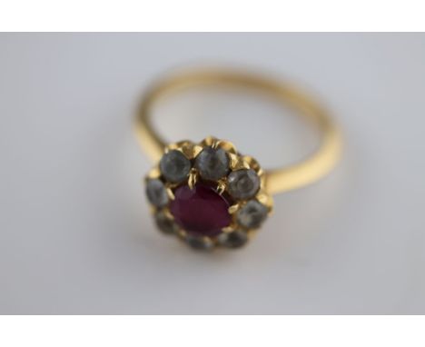 A synthetic ruby and white sapphire cluster unmarked yellow gold ring, the claw set centre round mixed cut synthetic ruby mea