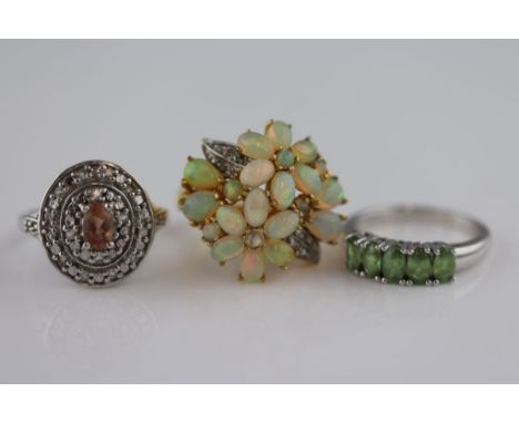 An opal and diamond fancy flower head cluster silver gilt ring, the oval, round and pear shaped cabochon cut precious white o