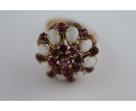 A ruby and opal unmarked rose gold fancy four tier cluster ring, the centre claw set round mixed cut ruby diameter measuring 