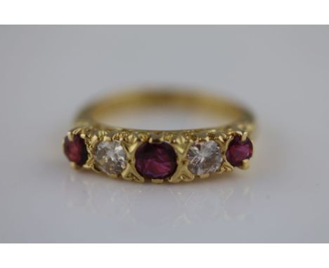 A ruby and diamond five stone 18ct yellow gold ring, the central largest round mixed cut ruby measuring approximately 4.5mm b