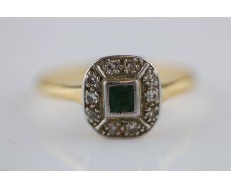 An Art Deco emerald and diamond yellow gold and white gold cluster ring, the central rub over set square cut emerald measurin