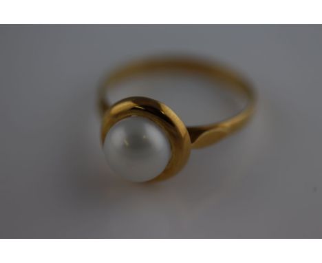 A single stone freshwater pearl ring, stamped '750', the button shaped pearl of approximately 7.1mm diameter, ring size O1/2