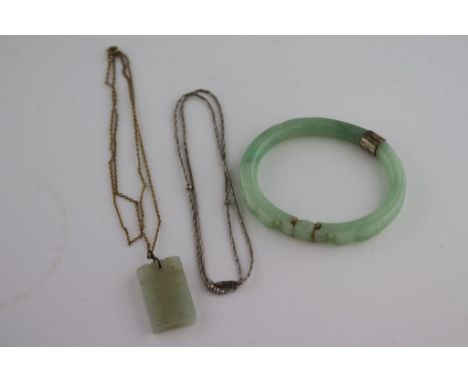 A carved jade bangle with white metal collar, dragon heads with shared ball in mouth together with a carved jade pendant and 