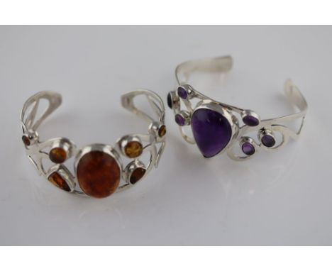 An amethyst silver bangle, the centre pear shaped cabochon cut amethyst measuring approximately 26mm by 17mm, six further ova