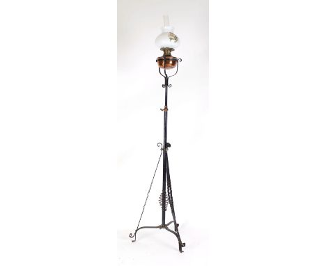 A late 19th century standard lamp, the scrolled adjustable copper and tole shaft supporting a copper oil lamp with an opaline