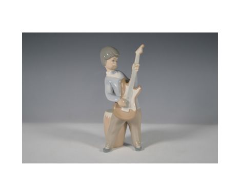 Presenting a charming Lladro porcelain figurine, model 1004614, titled Boy with Guitar. This delightful piece, designed by ar