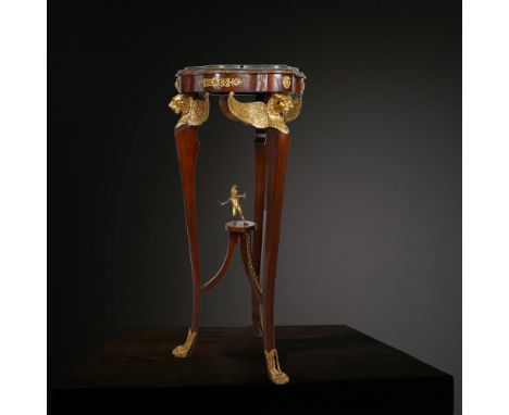 An exquisitely crafted French Empire-style mahogany gueridon table, adorned with gilt bronze mounts. The circular top is fram