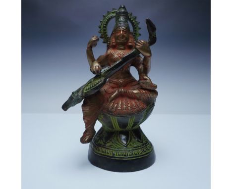 A beautifully detailed bronze and gilt statue of Saraswati, the Hindu goddess of wisdom, music, and arts, depicted playing th