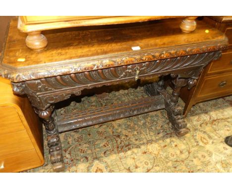 A late 19th century heavily carved oak centre table, having canted corners, single frieze drawer, raised on twin bulbous turn