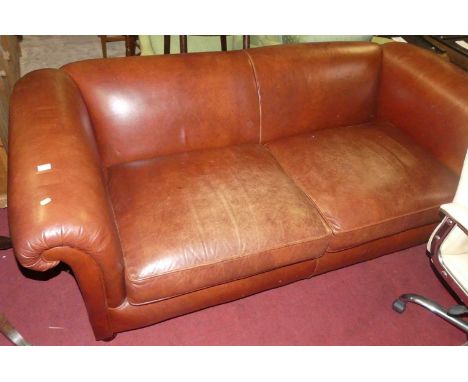 A contemporary tan leather three-seater sofa, having scroll arms and raised on turned bun supports, width 200cm