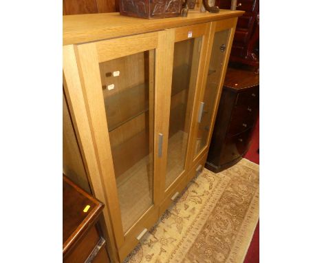 A contemporary light oak three door glazed china display cabinet, having three short lower drawers, w.127cm