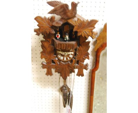 A carved and stained softwood cuckoo wall clock, with three weights and pendulum