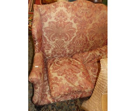 A circa 1900 mahogany framed red floral upholstered winged humpback two-seater sofa, raised on acanthus leaf carved cabriole 