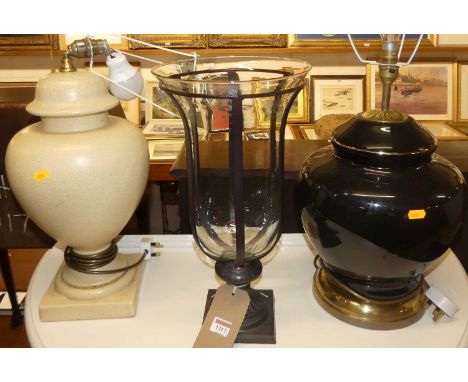 A black glazed ceramic bulbous form table lamp; together with a cream glazed example; and a metal and glass inset urn shaped 