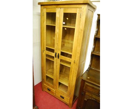 A contemporary light oak double door glazed display cabinet, having twin short lower drawers, width 89cm