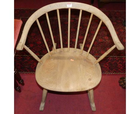 A faded Ercol light elm stickback tub rocking elbow chair