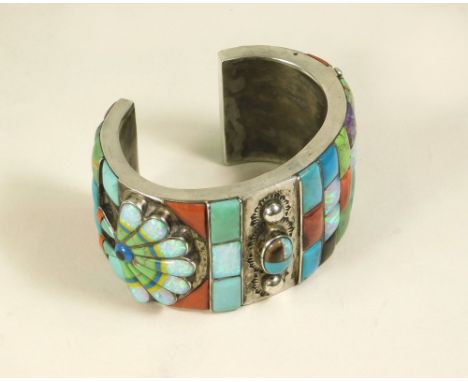 SILVER BANGLE. A substantial silver bangle, probably Navajo, pave-set throughout with semi precious coloured stones. Unstampe