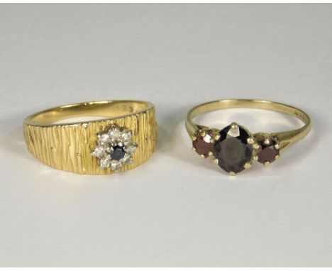 GOLD RINGS. An 18ct. gold sapphire &amp; diamond cluster ring with textured shank, size R &amp; a 9ct. gold garnet set dress 