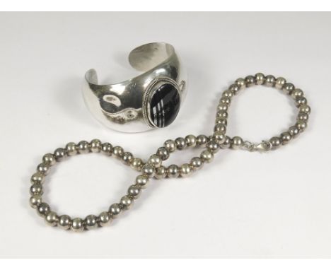 SILVER BANGLE ETC. A silver cuff bangle, the front set a black onyx inlaid with silver lines. Also, a silver bead necklace. L