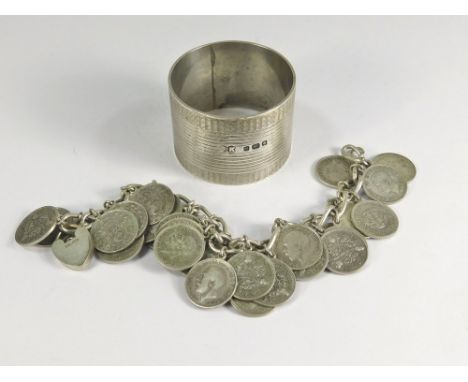 COIN BRACELET ETC.A silver bracelet with padlock clasp, hung with numerous silver threepenny pieces. Also, a silver napkin ri