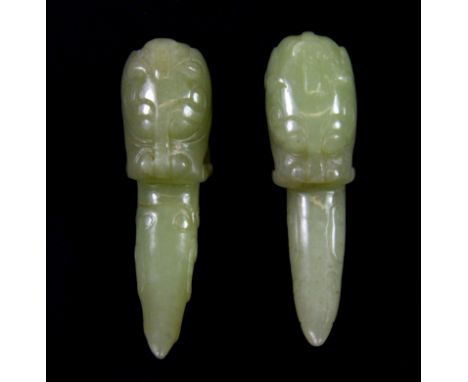 A pair of 19th century Chinese carved nephrite jade dragons head amulets each holding a tigers claw in its mouth, L. 6cms.