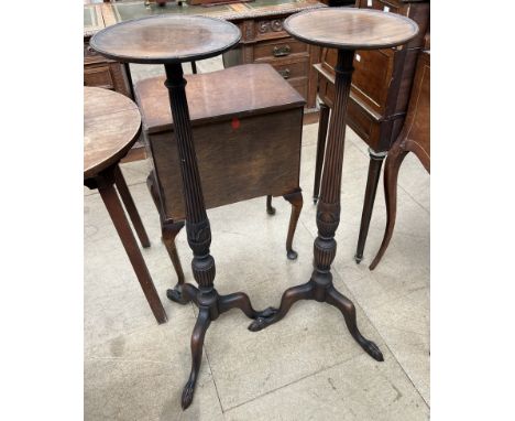 A pair of mahogany torcheres with circular tops above a tapering reeded column in a tripod base 
