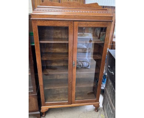 A 20th century oak display cabinet with a caddy top and a pair of glazed doors on cabriole legs and pad feet