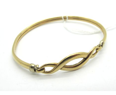 A Modern Bangle, of openwork design, hinged to the front, stamped "375" (5.3grams). 