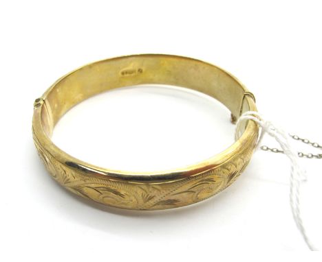A 9ct God Hinged Bangle, scroll engraved to front, hinged to snap clasp (dents) (15.5grams). 