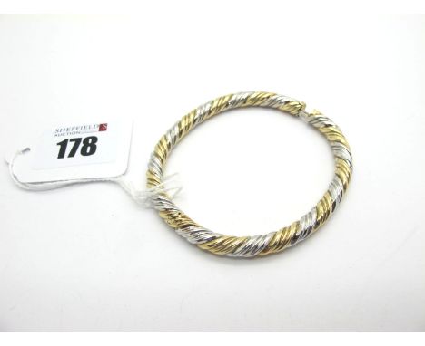 A Modern Two Colour Hinged Bangle, of twisted design, hinged to snap clasp, stamped "375" (18grams). 