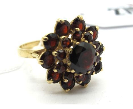 A Large 9ct Gold Garnet Cluster Dress Ring, of flowerhead design, claw set (finger size N1/2) (5.5grams). Lot 276 - The ring 