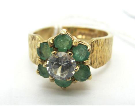 A 9ct Gold Emerald Set Cluster Dress Ring, claw set between bark textured shoulders (finger size L) (3.7grams). 