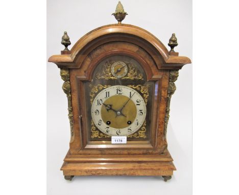 Early 20th Century figured walnut bracket clock, the broken arch case with gilt brass finials and mask head corner pilasters,