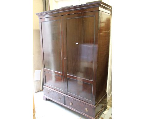 Edwardian mahogany wardrobe having moulded cornice above two panel doors, two drawers with brass ring handles and bracket fee