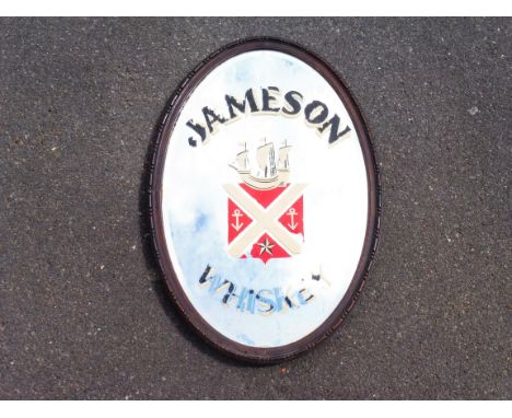 A wooden framed oval mirror with applied lettering advertising Jameson Whiskey, 22 1/2 x 32 1/2".