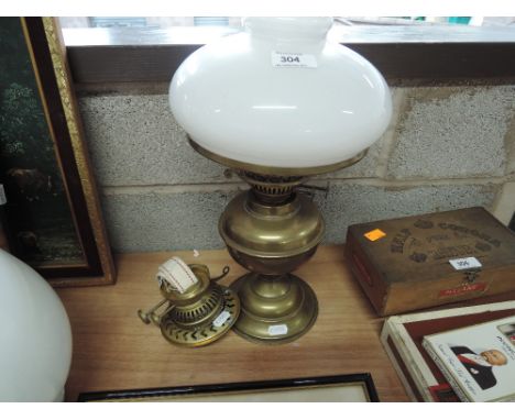 A vintage brass oil lamp with milk glass shade and spare burner