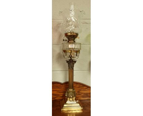 An Oil Lamp With Brass Corinthian Column Pedestal, decorated with four lion masks, having glass reservoir and shadeShade in o