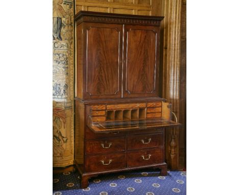 A George III mahogany secretaire cabinet,the moulded teardrop cornice above a two-door panelled upper section, opening to rev