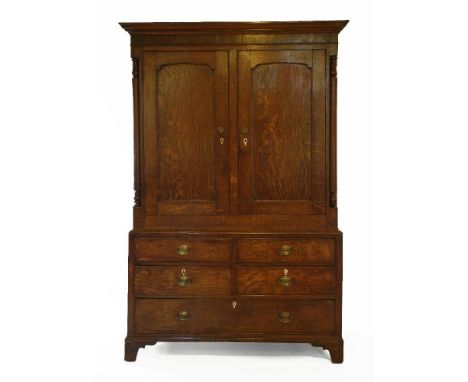 A George III oak linen press,now a hanging cupboard, the moulded cornice over two panelled doors within turned columns, the b