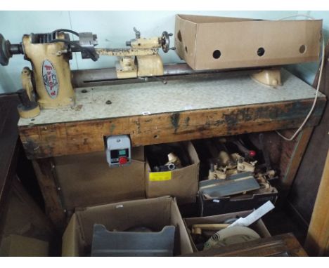 An old Myford woodworking lathe on an old bench with a large quantity of accessories 