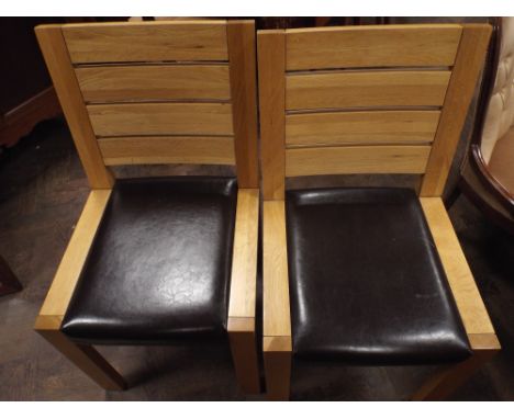 A set of six heavy light oak dining room chairs with brown leather seats 