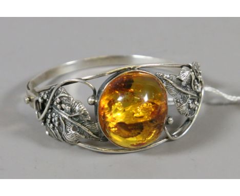 A ladies hinged silver and amber bangle decorated with leaves and vines.