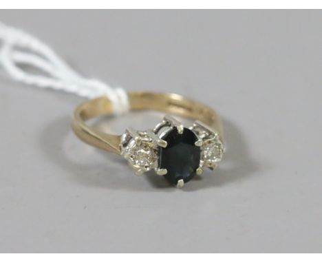 A 9ct gold ring set with an ovoid sapphire flanked by two diamonds, size K.