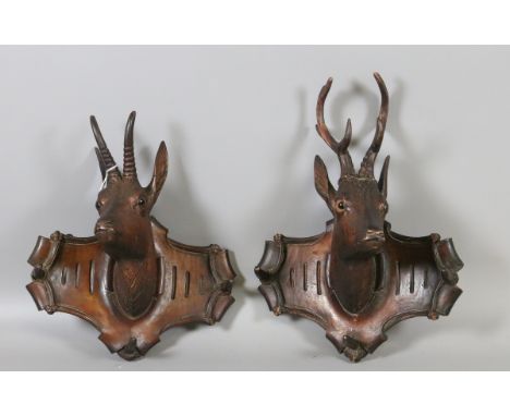 A pair of C19th Black Forest carved walnut coat hooks, one formed as a stag and the other an impala both with inset eyes.
